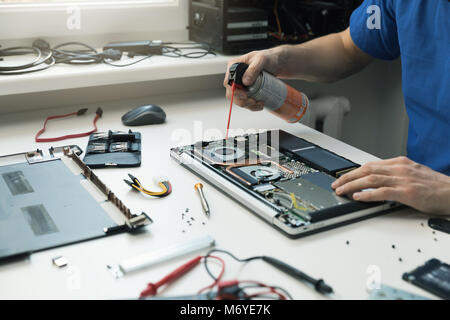Wartung - Techniker Ausblasen von Staub von Laptop Lüfter Stockfoto