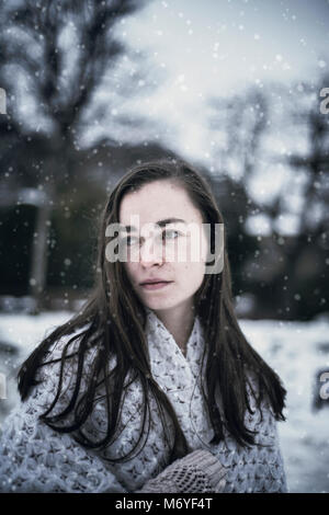 Langhaarige Frau in Schal gewickelt, verschneite Landschaft Stockfoto