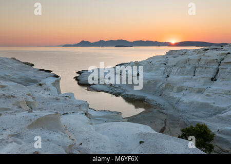 Strand und vulkanische Felsformationen bei sarakiniko an der Nordküste mit Sonnenaufgang über Kimolos Insel in Distanz, Sarakiniko, Milos, Kykladen, Ägäis S Stockfoto