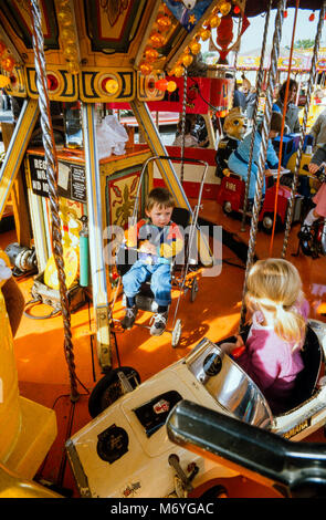 Junge Kinder auf einem kiddies Fahrt am Nottingham Goose Fair, eine jährliche Reisen Kirmes an der Walderholung in Nottingham, England statt, während der ersten Woche des Oktober. Archivierung Foto im Oktober 1987, England Stockfoto