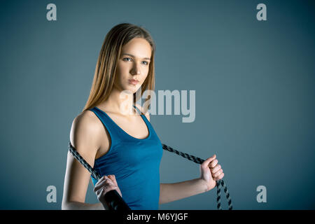 Fitness, Sport, Training, Menschen und Lifestyle Konzept - Porträt der jungen Frau oder jugendlich Übungen mit Expander oder Widerstand Band über Grau bl Stockfoto