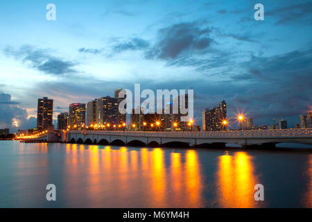 Blick von biscane Insel auf Downtown Miami über eine Brücke. Lampen auf ruhigem Wasser widerspiegelt. Stockfoto