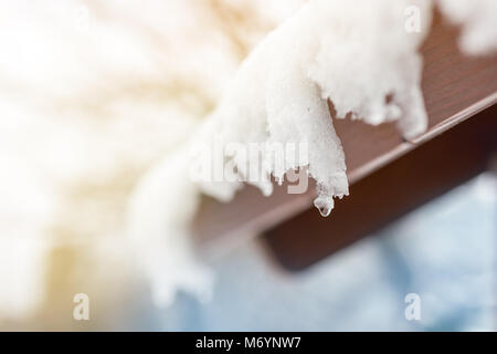 Nahaufnahme der schmelzende Schnee Eiszapfen auf dem Dach. Fallende Wassertropfen. Anfang des Frühlings. Sitzung Kälte und Hitze Konzept. Frischer Frühling Natur Hintergrund. Stockfoto