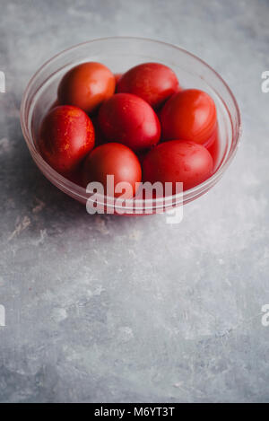 Satz von sechs Farben Rot, in eine Glasschale für Ostern, Färbung mit Rotstich Eier über einen konkreten Hintergrund, grau Stockfoto