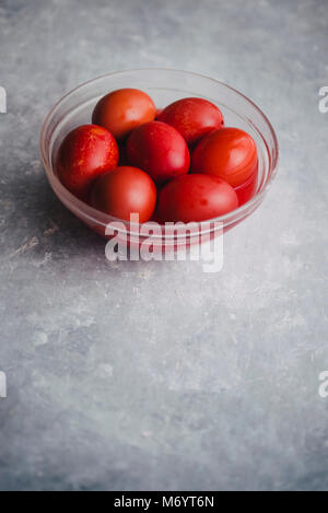 Satz von sechs Farben Rot, in eine Glasschale für Ostern, Färbung mit Rotstich Eier über einen konkreten Hintergrund, grau Stockfoto