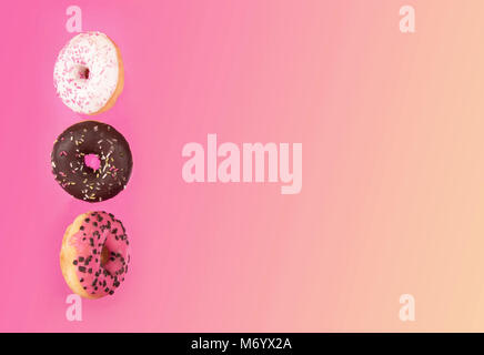 Bunt glasierter Krapfen in motion auf rosa Hintergrund. Stockfoto