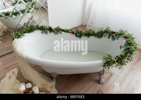 Elegante, freistehenden Badewanne und mit Blumen geschmückt. Im Wasser schwimmen Zitrusfrüchte. Die Atmosphäre der Entspannung, Entspannung Stockfoto