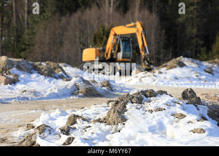 Baustelle im Winter, mit Gelb mittlere Hydraulikbagger defokussierten im Hintergrund. Selektive konzentrieren. Stockfoto