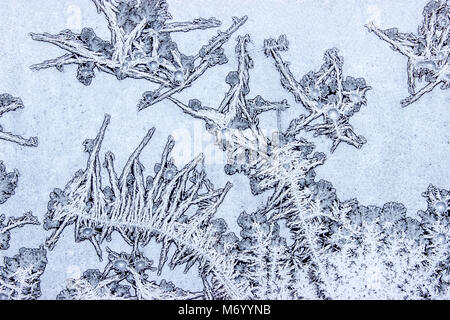 Frost schafft verschiedene Ornamente, die menschlichen Figuren auf dem Fenster Stockfoto