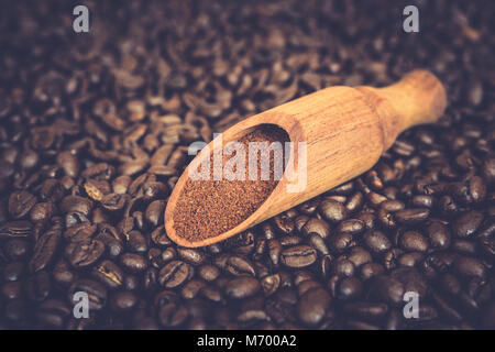 Holz- Schaufel mit gemahlenem Kaffee auf gerösteten Kaffeebohnen Hintergrund Stockfoto