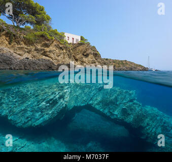 Felsige Küste mit einem kleinen Haus und eine natürliche Felsformation Unterwasser im Mittelmeer, in der geteilten Ansicht oberhalb und unterhalb der Wasseroberfläche, Spanien Stockfoto