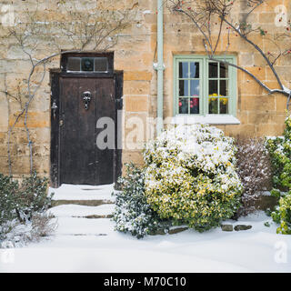 Stanton Steinhütte Holztür und Stufen im Winterschnee. Stanton, Cotswolds, Worcestershire, England Stockfoto