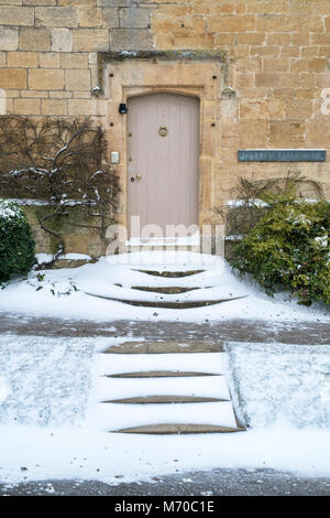 Stanton Stein Bauernhaus Holztür und Treppen im Winterschnee. Stanton, Cotswolds, Worcestershire, England Stockfoto