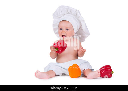 Ein lustiges kleines Mädchen in der Kleidung eines Chefs isst, Pfeffer. Stockfoto