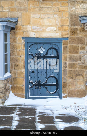 Broadway Steinhaus grau besetzt Holztür im Winterschnee. Broadway, Cotswolds, Worcestershire, England Stockfoto