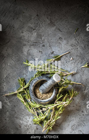 Zweig Bündel frischem Rosmarin und getrockneten Blätter Gewürz Mörser pounder Essen Konzept Gras Getreide Gewürze Ernte Kräuter für Medizin und Kochen auf Grau Bac Stockfoto