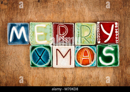 Die Worte "Merry Xmas" aus Keramik Buchstaben auf Holz Textur gemacht Stockfoto