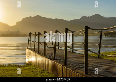 Bild des Sonnenuntergangs an der Lagune Rodrigo de Freitas in Rio de Janeiro mit Bergen, Pier und charakteristischer Kontur Stockfoto