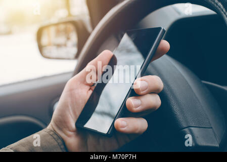 Man Autofahren und mit Handy für Sms, gefährlich und rücksichtslos Verhalten im Verkehr, die Unfälle verursacht. Stockfoto