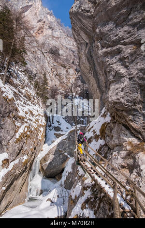 Junge Frauen wandern über Holz- Leitern und Brücken durch verschneite Schlucht Baerenschuetzklamm mit gefrorenen vereisten Wasserfälle Stockfoto