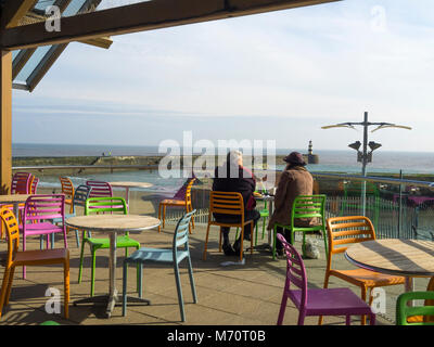 Ein paar genießen Sie einen Snack am Morgen im Winter Sonne auf dem Balkon der Blick Café in Seaham Hafen Stockfoto