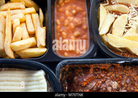 Auswahl von gefrorenem, verarbeitet, fertige Nahrungsmittel, die aus Kartoffelchips, Gehacktes, Lasagne in Schwarz, Kunststoff Behälter. Mikrowelle Mahlzeiten bereit zu h Stockfoto