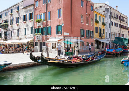 Gondeln auf dem Rio San Barnaba, Campo San Barnaba, Dorsoduro Venedig, Italien mit dem Gondoliere sitzen, plaudern und die Touristen essen in Restaurants Stockfoto