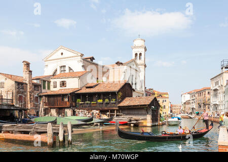 Gondel mit Touristen in Rio di San Trovaso im San Trovaso Squeroor Gondel Bootswerft in Cannaregio, Venice, Italien mit San Trovaso Kirche hinter Stockfoto