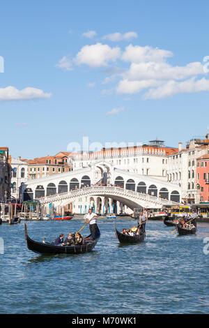 Linie der Gondeln mit Touristen auf dem Canal Grande, Rialto Brücke, Venedig, Venetien, Italien genießen eine Sightseeing Tour in diesem Unesco Weltkulturerbe Sitzen Stockfoto