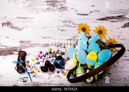 Ostern Lebkuchen Kekse, Schokolade, Eier und bunten Bonbons auf hölzernen Tisch. Hasen und Eier. Grußkarte. Blick von oben. Kopieren. Stockfoto