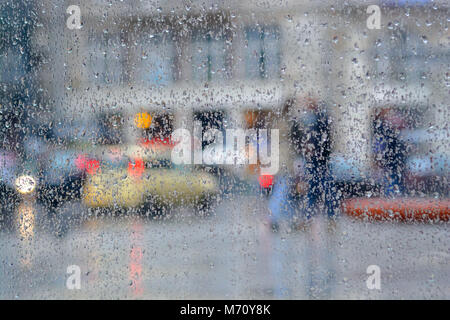 Regentropfen auf das Glas gegen verwackelte city street scene Stockfoto
