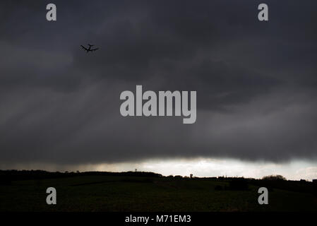 Thaxted Essex England. Flugzeug Landung am Flughafen Stansted über John Webb's Mühle erbaut im Jahre 1804 fliegen. März 2018 Sturm, Wolken und Regen approc- Stockfoto