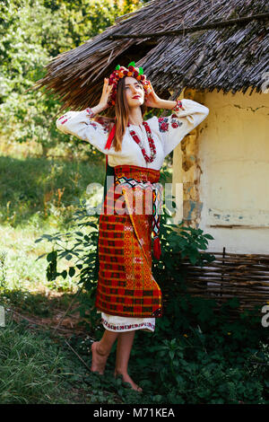 Schöne Ukrainische Mädchen in Nationale Kleidung gestickt auf einer hölzernen Hütte im Sommer Stockfoto