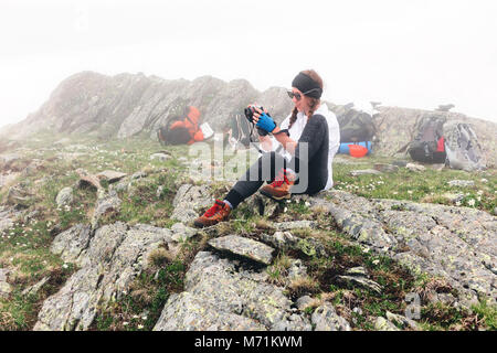 Ein Mädchen fährt in die Berge Fotos mit einer Kamera, camping Rucksack Hintergrund. Das Konzept der Abenteuer, Lifestyle Wanderungen. Stockfoto