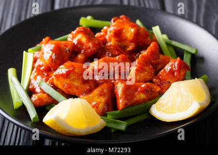 Spicy chicken Stücke in Chili Sauce mit grünen Zwiebeln und Zitronensaft close-up auf einem Teller. Huhn 65. Horizontale Stockfoto