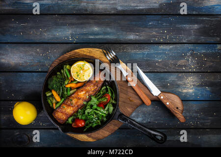 Gegrilltes Lachsfilet in einer Pfanne, Gemüse, Rucola mit Zitrone. Stockfoto