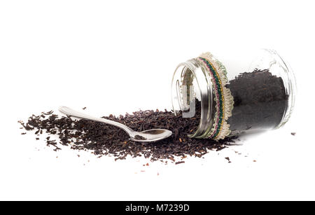 Isolierte Glas Glas mit fermentierten grosse Blätter von Ceylon Tee auf weißem Hintergrund. Auf der Seite gibt es auch einen Teelöffel Stockfoto