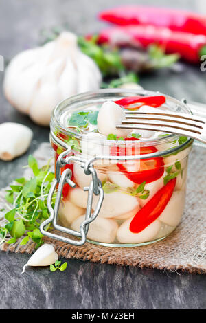 Marinierter Knoblauch mit gemischten Chilis und Kräuter im Glas Stockfoto