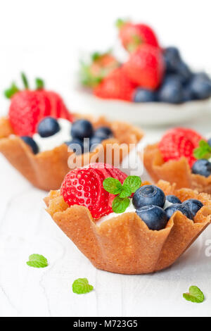 Brandy snaps Körbe mit weichen Frischkäse und Beeren auf weißem Hintergrund Stockfoto