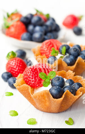 Brandy snaps Körbe mit weichen Frischkäse und Beeren auf weißem Hintergrund Stockfoto