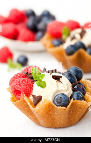 Brandy snaps Körbe mit weichen Frischkäse und Beeren auf weißem Hintergrund Stockfoto