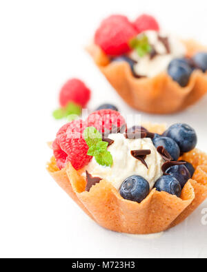 Brandy snaps Körbe mit Eis und Beeren auf weißem Hintergrund Stockfoto