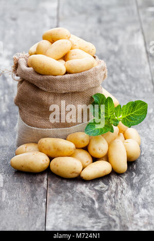 Baby Kartoffeln in sackleinen Sack auf Holz- Hintergrund Stockfoto