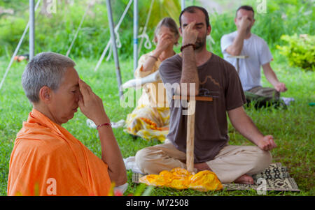 Menschen üben yogische Atemtechnik genannt Pranayama mit Unterstützung stick Danda in Yoga Retreat auf Fidschi Insel. Lehrer leitet drei Junge Stockfoto