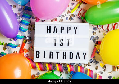 Glücklich 1. Geburtstag Feier Nachricht auf ein Leuchtpult mit Ballons und Konfetti Stockfoto