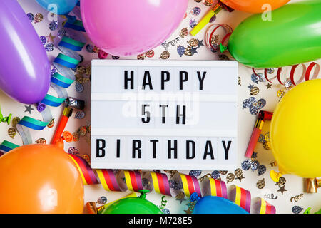 Glücklich 5. Geburtstag Feier Nachricht auf ein Leuchtpult mit Ballons und Konfetti Stockfoto