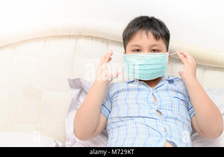 Beleibte Fat Boy Verschleißschutz Maske gegen Grippe im Bett Zimmer zu schützen, Gesundheit und kranken Kind Konzept Stockfoto