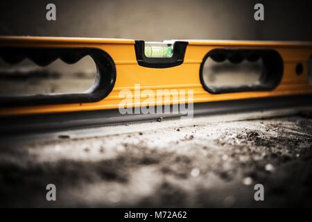 Bau Wasserwaage Werkzeug Instrument auf der rohen Betonboden. Closeup Foto. Stockfoto