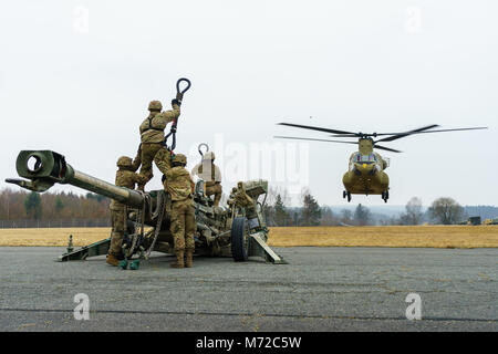 Eine CH-47 Chinook Hubschrauber Besatzung zu Unternehmen B zugeordnet sind, 2. Allgemeine Unterstützung Aviation Battalion, 227 Aviation Regiment, 1 Combat Aviation Brigade, 1.Kavallerie Division, bereitet in Position über artilleristen mit Batterie B, Field Artillery Squadron, 2.Kavallerie Regiments, mit Schlinge legen Sie ein M777 Haubitze während der Proben auf einem Flugplatz in der Nähe von Grafenwöhr, Deutschland März 6, 2018. Soldaten der beiden Einheiten kamen zusammen, um Beziehungen zu Schulen und bei der dynamischen Front 18, eine jährliche US-Army Europe Übung zur Verbesserung der Interoperabilität der US-Armee, gemeinsamen Dienst stärken und Alliierten Stockfoto