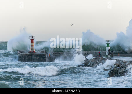 Fischer braving enorme Wellen, die hier zu sehen sind krachend gegen die Wellenbrecher von Kalk Bay Harbor in Kapstadt, Südafrika. Stockfoto